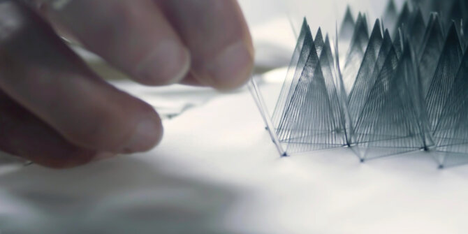 Fingers weaving fine threads into a geometric pattern, macro – DS Savoir-faire in Motion