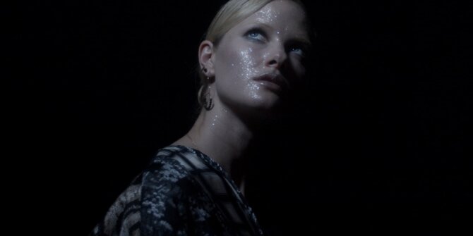 Model with glitter on her face looking up in total darkness – Ginette NY Ajna jewellery film