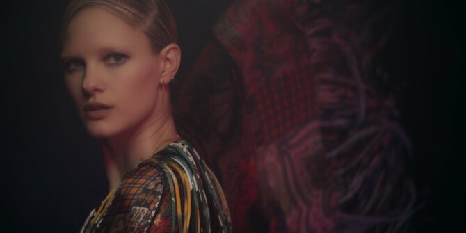 Model glancing over her shoulder in front of dark red fabric – Ginette NY Ajna jewellery film