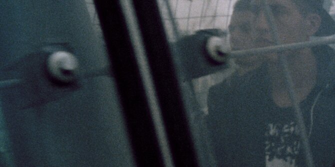 Teenager in a cap behind a wire fence, shot on 16 mm film – Bundesliga Stiftung commercial
