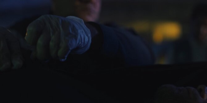 Gloved hand lifting a sheet at a night crime scene – OPJ Season 5 Double Lady