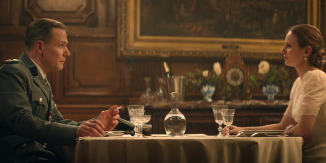 German officer and a woman dining face to face in a wood-panelled room, 1944 – Rhinozeros